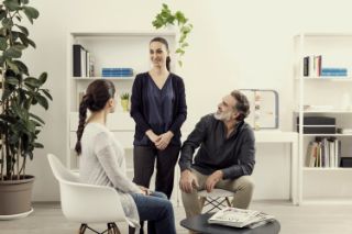 A couple talking with an Amplifon hearing professional dressed in black