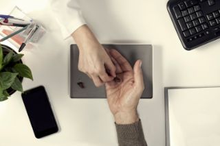 A hearing professional handing an hearing aid to a male client