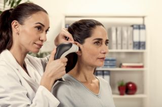 Un profesional auditivo de Amplifon revisa la audición de una mujer