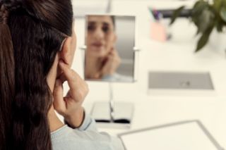 Woman looking in mirror with hearing aids