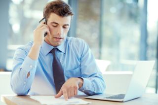 Man using a laptop while answering a phone call