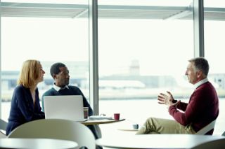 Three people sitting around a table having a work meeting
