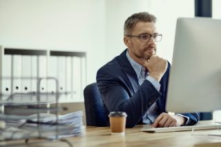 A man works on his computer with a cup of coffee