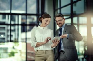 Woman and man smiling while looking at a tablet