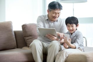 Un abuelo con su cuaderno mostrando algo a su nieto en un teléfono inteligente