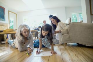 A little girl is drawing with her grandmother during a family reunion at home