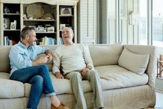 A father and his son spending time together and laughing sitting on a couch