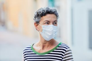 A senior woman wearing a face mask in the street