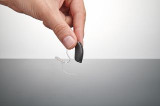 Someone picking up a hearing aid