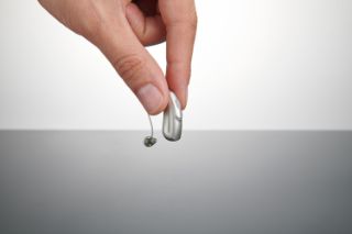 Someone picking up a hearing aid