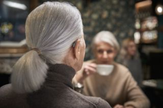 Woman wearing hearing aid having coffee with a friend