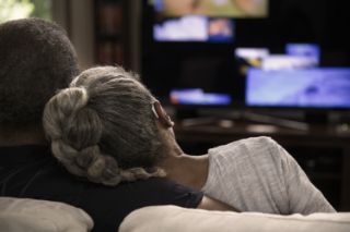 A elderly couple watching TV together on a couch
