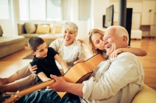 Un abuelo toca la guitarra para su familia
