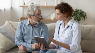 A female physicist and a senior man sitting on a couch talking