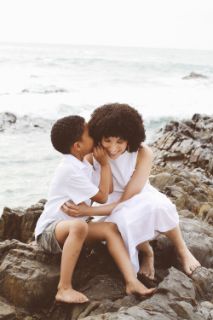 A child whispering something in his mother's ear on the seashore