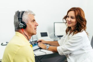 Un hombre que realiza la prueba de detección auditiva con una profesional de la audición de Amplifon