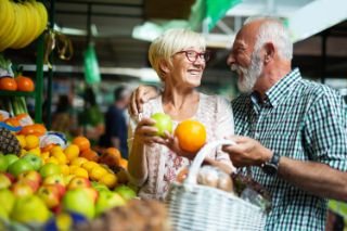 Una pareja de adultos mayores comprando frutas en el mercado