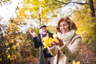 A senior couple enjoying a walk in the woods during the fall