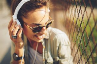 A young woman wearing sunglasses and headphones listening to music
