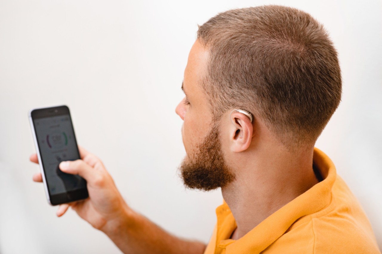 Man using smartphone while wearing hearing aid