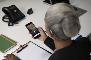 Una mujer de la tercera edad con un audífono en el oído izquierdo usa una aplicación en su teléfono inteligente