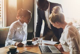 Three people having a work meeting around a table