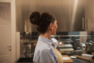 A senior woman seen in profile cooking in her kitchen