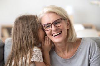 A granddaughter whispering in her grandmother's ear