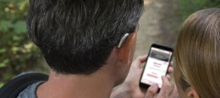 A man using an app on his smartphone with his wife next to him