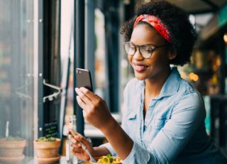 Una mujer sentada en un café mirando algo en su teléfono inteligente