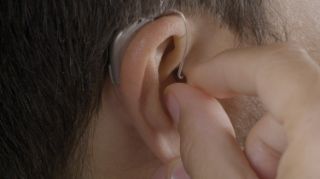 Un hombre colocando un audífono en su oído derecho