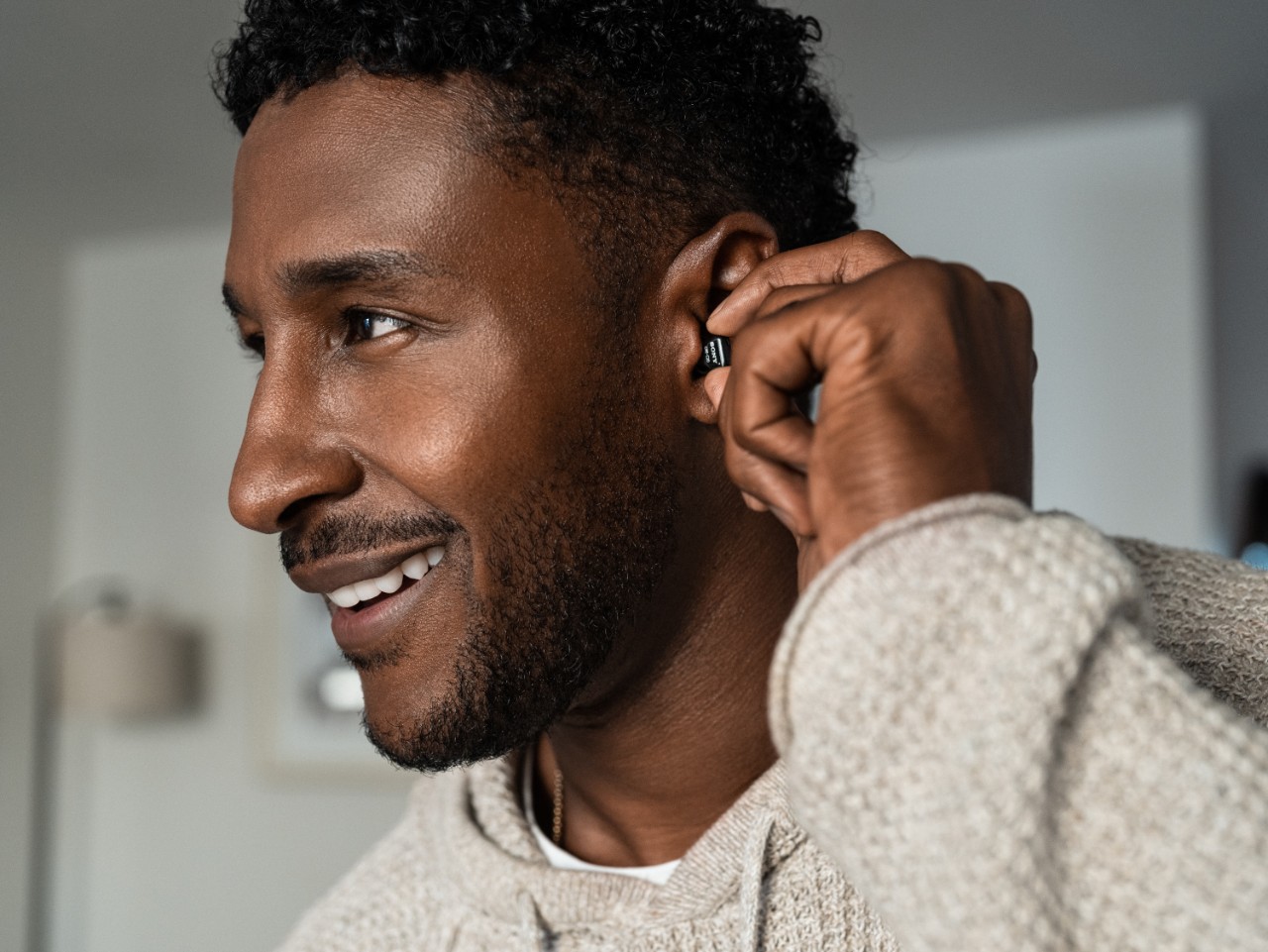 Man touching his hearing aid and smiling