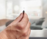 Hand holding tiny hearing aid