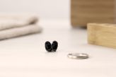 Audífonos intraurales sobre una mesa junto a un anillo