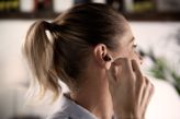 Una mujer colocándose su audífono intraauricular en el oído derecho