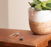 Audífonos intraurales sobre una mesa junto a llaves y un jarrón