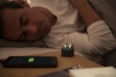 Man sleeping in his bed with rechargeable hearing aids charging in their charger