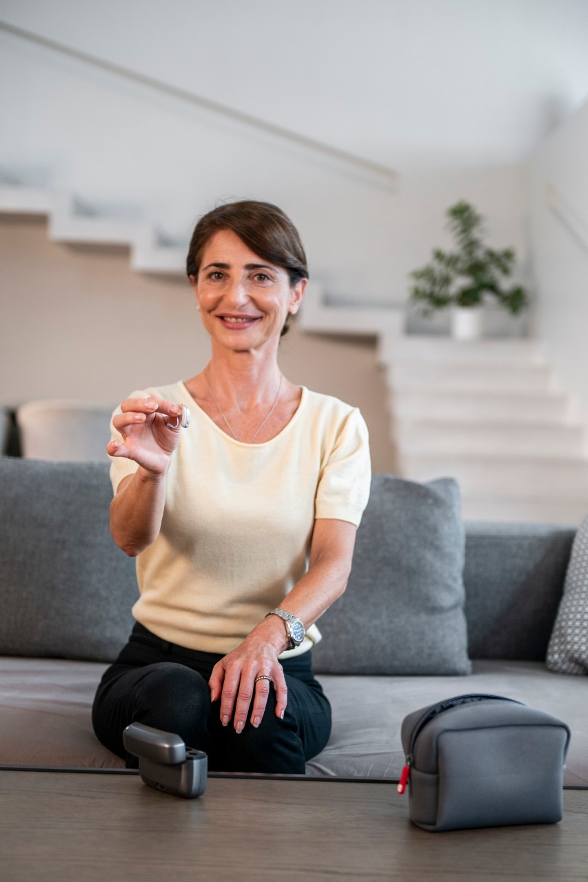 Woman showing hearing aid and smiling