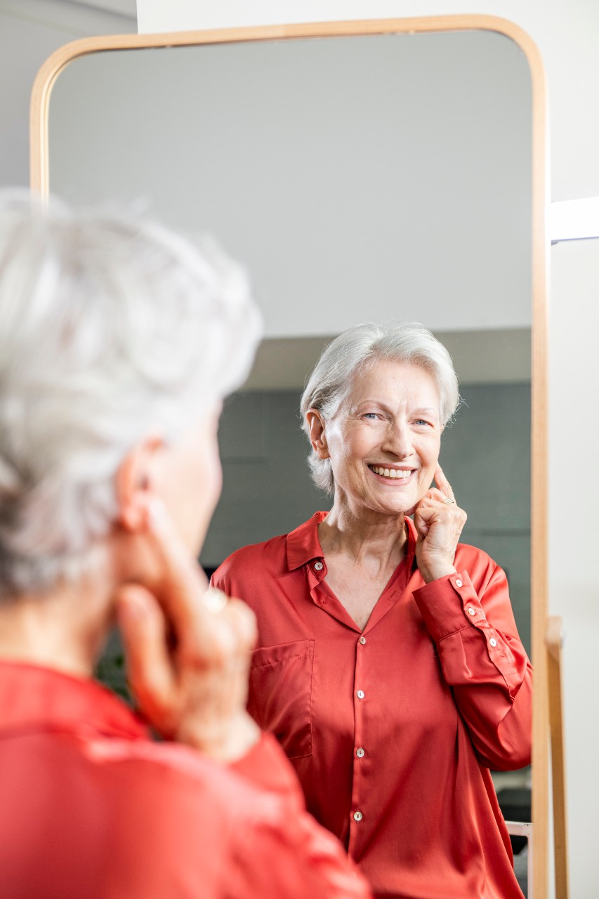 Woman looking at the mirror wearing hearing aid