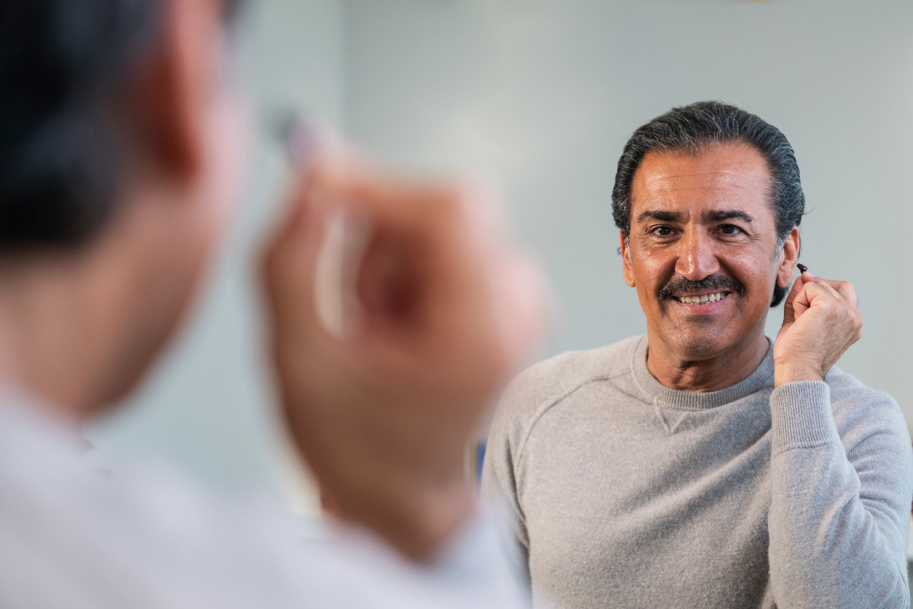 Male client adjusting hearing aid