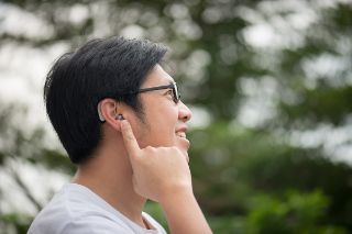 A young man touching his ear with a hearing aid