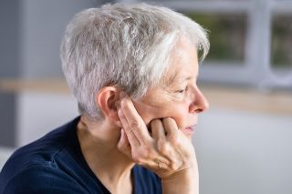 Elderly woman touching her sore ear