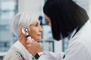 A doctor visiting the ear of a patient