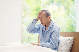 A senior man touching his forehead