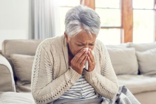 Elderly woman blowing her nose