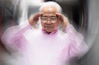 Elderly man holding his head due to headache