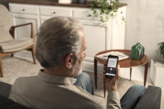 Man wearing a hearing aid and using his smartphone