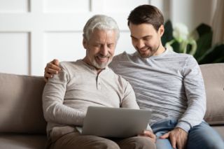 Two men sitting on a sofa watching their tablet