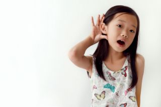 Child cupping her hand behind her ear to hear better 
