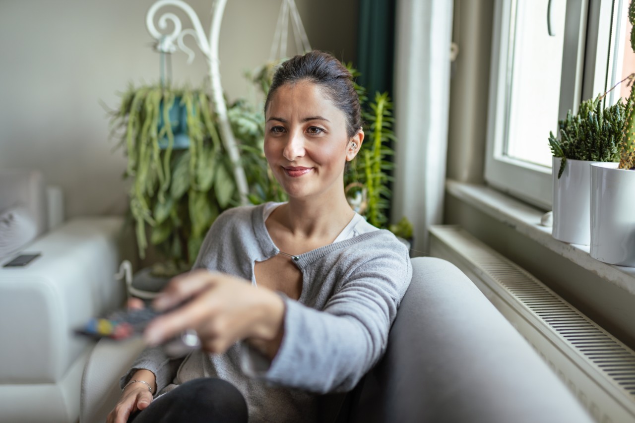 A young woman watching tv with hearing aid